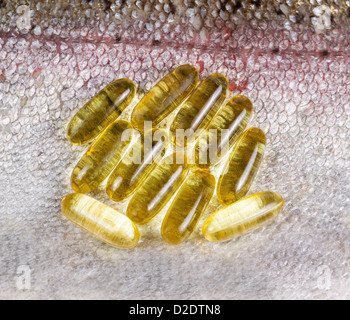 Mehrere goldene Fischölkapseln legen auf frische saubere Lachshaut Stockfoto