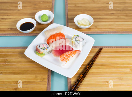 Frische japanische Sushi auf weißen Teller, Stäbchen, Sojasauce auf Bambus-Tischsets Stockfoto