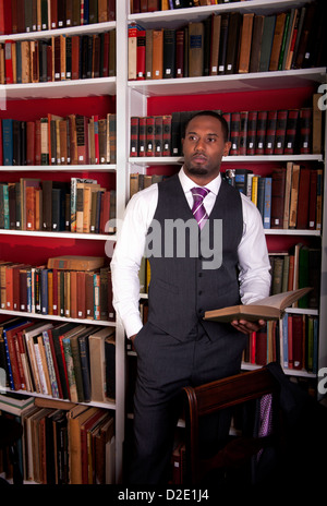 Ein gut gekleideter Mann (Afroamerikaner), der in der Heimatbibliothek steht Stockfoto
