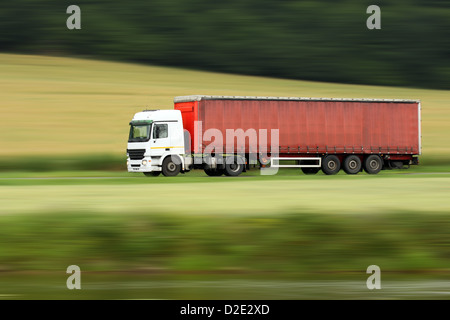 große rote LKW Beschleunigung auf der Autobahn mit unscharfen Landschaft Panorama im Hintergrund Stockfoto