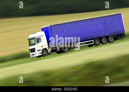 große blaue LKW Beschleunigung auf der Autobahn mit unscharfen Landschaft Panorama im Hintergrund Stockfoto