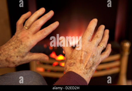 Alten Womans kalte Hände Erwärmung auf ein Feuer Stockfoto