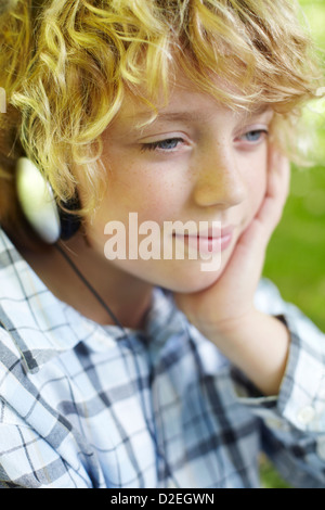 Junge, anhören von MP3-Player mit Kopfhörern im Sommerpark Stockfoto