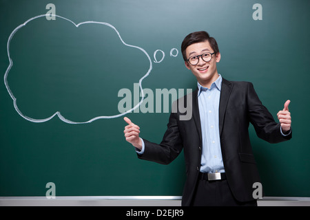 Humorvolle männliche Lehrer tun Daumen oben im Klassenzimmer Stockfoto
