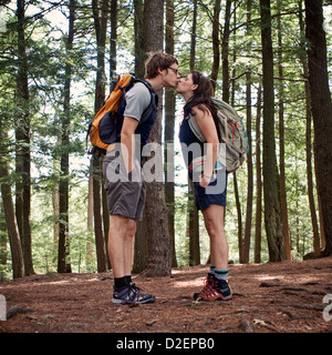 Ein junges Paar küsst sich beim Wandern im Wald. Stockfoto