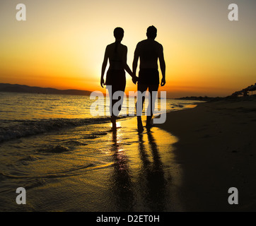 Paar am Strand entlang gegen Sonnenuntergang Stockfoto