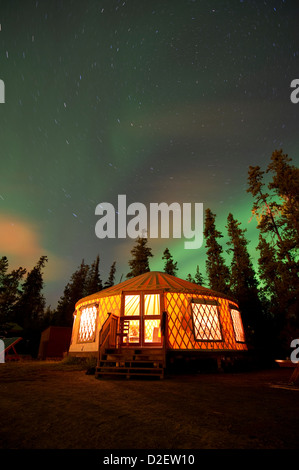 Aurora Borealis (Nordlicht) über eine beleuchtete Jurte außerhalb von Whitehorse im Yukon Territorium, Kanada. Stockfoto