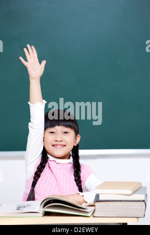 Fröhliche Schülerin Erhöhung Hand im Klassenzimmer Stockfoto