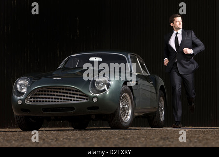 Mann läuft neben DB4 Sportwagen von Aston Martin Stockfoto