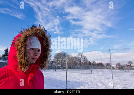 Ein junges Mädchen Spaziergänge durch einen verschneiten Park in Croydon, Surrey Vereinigtes Königreich Stockfoto