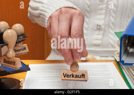 ein Stempel mit der deutschen Aufschrift verkauft wird in der Hand gehalten. Stockfoto