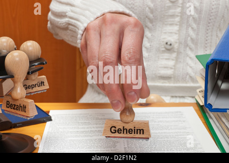 eine Briefmarke mit dem deutschen Inschrift Geheimnis ist in der Hand gehalten. Stockfoto