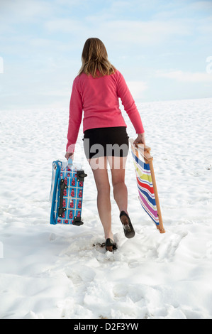 Winterurlaub bedeckt Urlauber zu Fuß über Schnee, Feld tragen Koffer & Liegestuhl Stockfoto