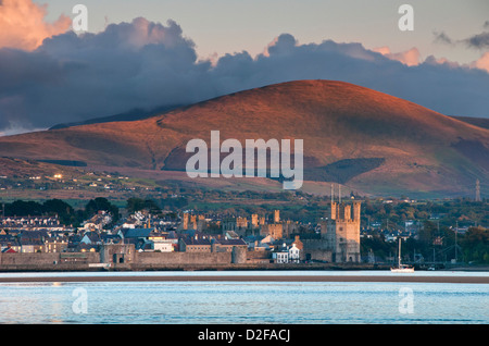 Caernarfon Castle und Menai Straits unterstützt von Moel Eilio gesehen von Anglesey, Gwynedd, Nordwales, UK Stockfoto