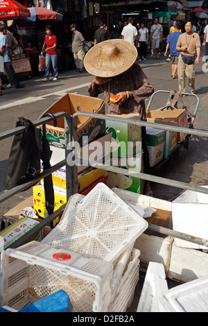 Hong Kong, China, Frau mit Strohhut in Abfällen nach Nahrung suchen Stockfoto