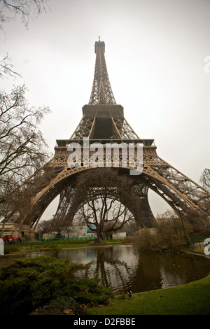 Der Eiffelturm an einem Wintertag, eingerahmt von blattlosen Bäumen und einem reflektierenden Teich darunter, der den zeitlosen Charme von Paris, Frankreich, zeigt Stockfoto