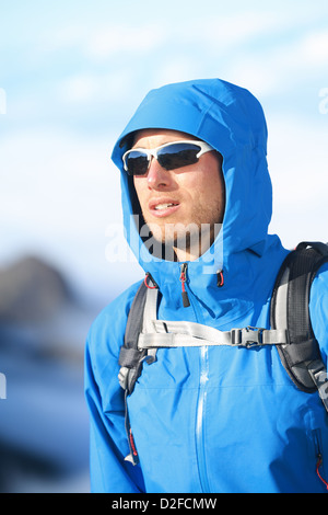 Hübscher Junge männliche Wanderer alpine Kleidung schwer Softshell-Jacke oben im Hochgebirge über den Wolken Stockfoto