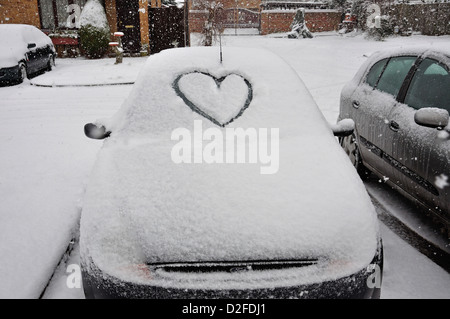 Auto mit Herzen gezogen im Schnee auf Windschutzscheibe, Stanwell Moor, Surrey, England, Vereinigtes Königreich Stockfoto