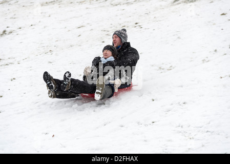 Zwei Menschen schieben Hang hinunter auf Schlitten nach starkem Schneefall Januar 2013 mit Menschen Spaß und spielen im Schnee Stockfoto