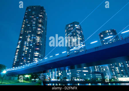 riesige Wohn Wolkenkratzer mit beleuchteten Fenstern über beleuchtete Hängebrücke Struktur in Tokio, Japan Stockfoto