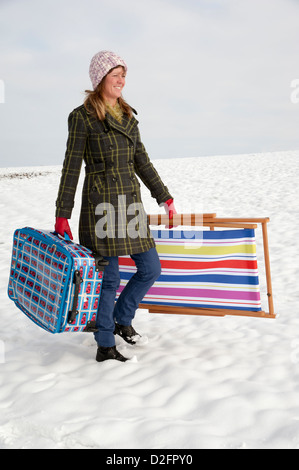 Winterurlaub bedeckt Urlauber zu Fuß über Schnee, Feld tragen Koffer & Liegestuhl Stockfoto