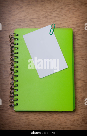 grüne Notizbuch auf einem Schreibtisch aus Holz Stockfoto