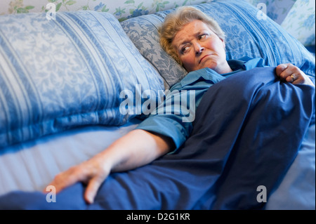 Reife Frau im Bett allein liegen und Blick auf den leeren Platz neben ihr Stockfoto