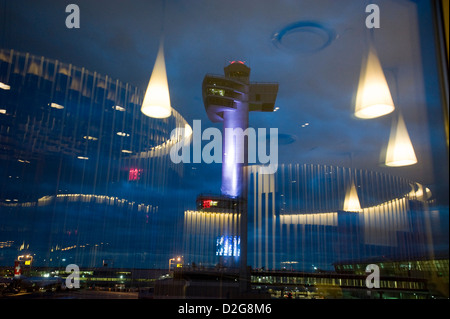 Der Kontrollturm ist in der Abenddämmerung am John F. Kennedy Airport, JFK Airport, New York, USA beleuchtet. Fotografiert mit den Überlegungen von Lichtern in der Virgin Airways Upper Class lounge Stockfoto