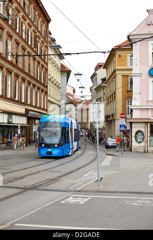 Eine blaue Straßenbahn fährt durch die charmanten Straßen von Graz, Österreich, und verbindet moderne öffentliche Verkehrsmittel mit historischer Architektur im Stadtzentrum Stockfoto