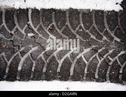 Print Auto Reifen auf Asphalt auf nassem Schnee Stockfoto
