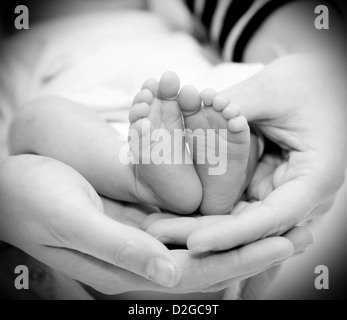 Kleine Füße Baby hält seine Mutter in ihren Händen. Stockfoto