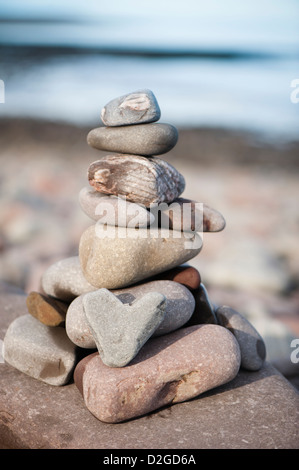 Herzförmigen Stein mit einem Stapel von Steinen am Strand von Porlock Weir, Somerset, England, Vereinigtes Königreich Stockfoto