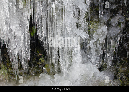 Bildung von Eiszapfen auf Seite der Berghöhle Felsen im Winter Hintergrund Stockfoto