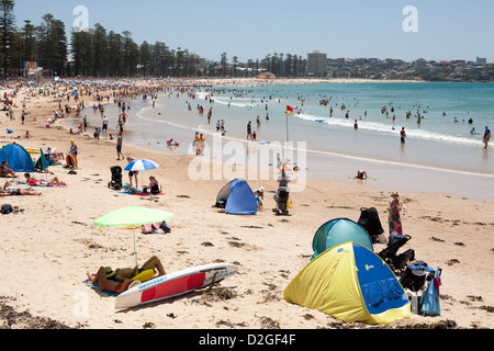 Überfüllten Strand voller Sonnenanbeter und Schwimmer zwischen den Flaggen auf ein Surf Lifesaving bewachten Strand Manly Sydney Australia Stockfoto