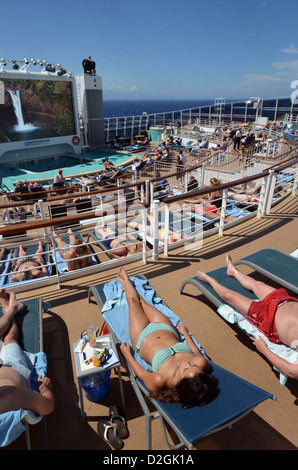 Passagiere, die zum Sonnenbaden am Meer auf dem Achterdeck der Kreuzfahrt Schiff Norwegian Epic. Stockfoto