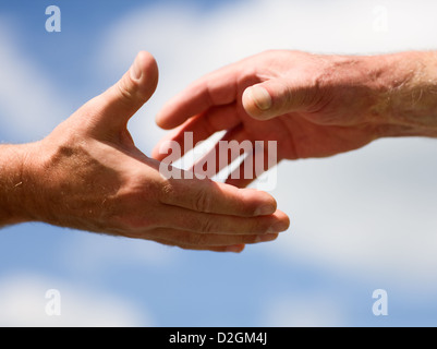 Zwei Hände ausstrecken miteinander gegen blauen Himmel Stockfoto