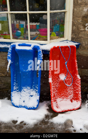 Schlitten im Schnee vor Hardware-Geschäft bei Hay-on-Wye Powys Wales UK bedeckt Stockfoto