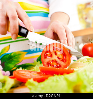 Frauenhand Tomate hinter frisches Gemüse schneiden. Stockfoto