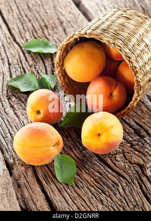 Aprikosen mit Blättern auf dem alten Holztisch. Stockfoto