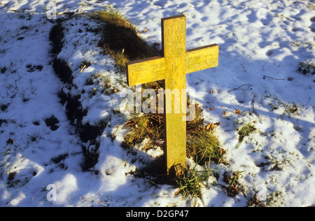 Schlichte Kruzifix aus Holz Grab Marker an Spitze der jüngsten Grab bedeckt im Schnee in warmen Winter-Licht Stockfoto