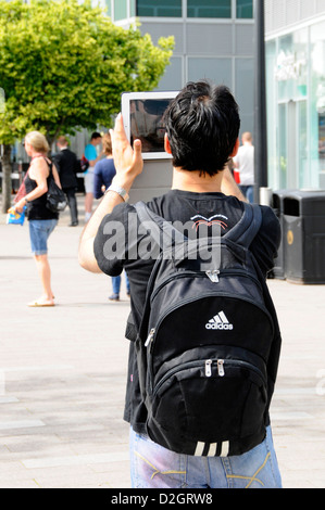 Junge Menschen, die im Besitz einer Apple Ipad in der Straße ein Foto auf seinem Tablet Greenwich Peninsula London England UK zu nehmen Stockfoto