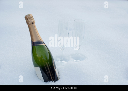 Flasche Champagner und zwei Gläser im Schnee Stockfoto