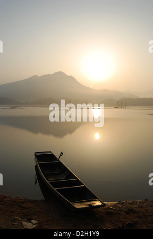 Einzelne einsame Boot entlang der Kante der See als die Morgensonne steigt über die Berge, Taiping Lake, Provinz Anhui, China Stockfoto