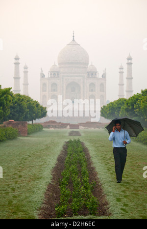 Indien, Uttar Pradesh, Agra, Mann mit Regenschirm spazieren im Park gegenüber Taj Mahal Stockfoto