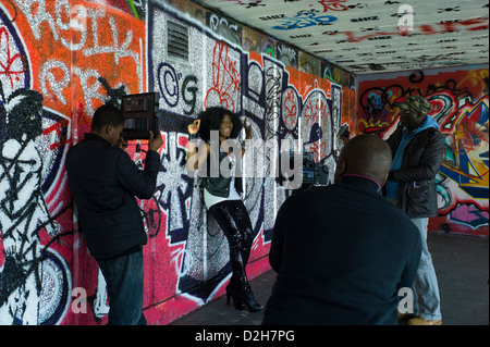 London, Southbank, Riverside, Embankment junge schwarze Mädchen Sängerin vor Graffiti, street-Art video-Aufnahmen. Stockfoto