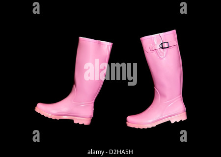 Ein paar rosa Gummistiefel oder Gummistiefel vor einem schwarzen Hintergrund positioniert, dass sie aussehen, wie sie Fuß sind Stockfoto