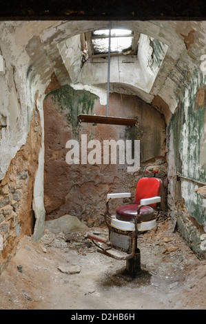 Barber Shop Stuhl in verfallenden Gefängniszelle, gruselig und verwunschene Ruinen an der Eastern State Penitentiary, Philadelphia, PA, USA. Stockfoto