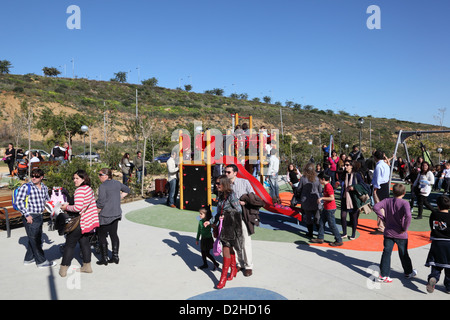 Eltern mit ihren Kindern auf einem überfüllten Spielplatz. Estepona, Andalusien, Spanien Stockfoto