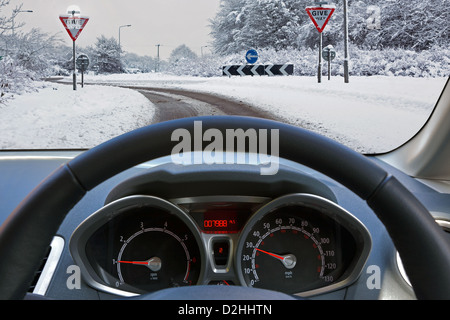 Autofahrer Sicht durch die Windschutzscheibe des Fahrzeugs während der Fahrt auf dem Schnee bedeckt Straße Stockfoto