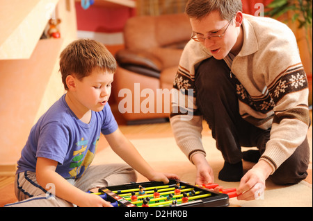 Nahaufnahme eines kleinen Jungen und seinem Vater Spielbrett Fußballspiel am Boden. Stockfoto